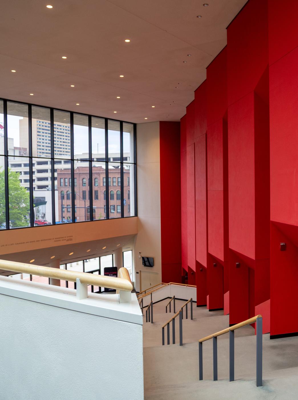 Red-walled lobby staircase inside the Des Moines Civic Center